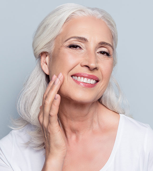 older woman smiling while touching face