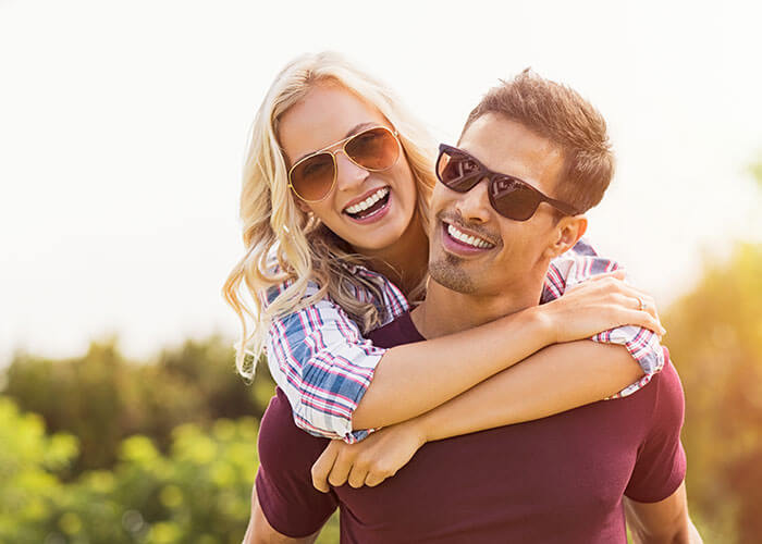 couple with glasses smiling outdoors
